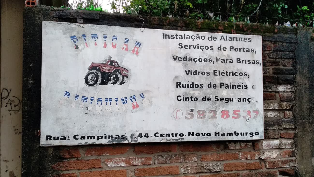 Placa pintada à mão na fachada da Piticar listando os serviços